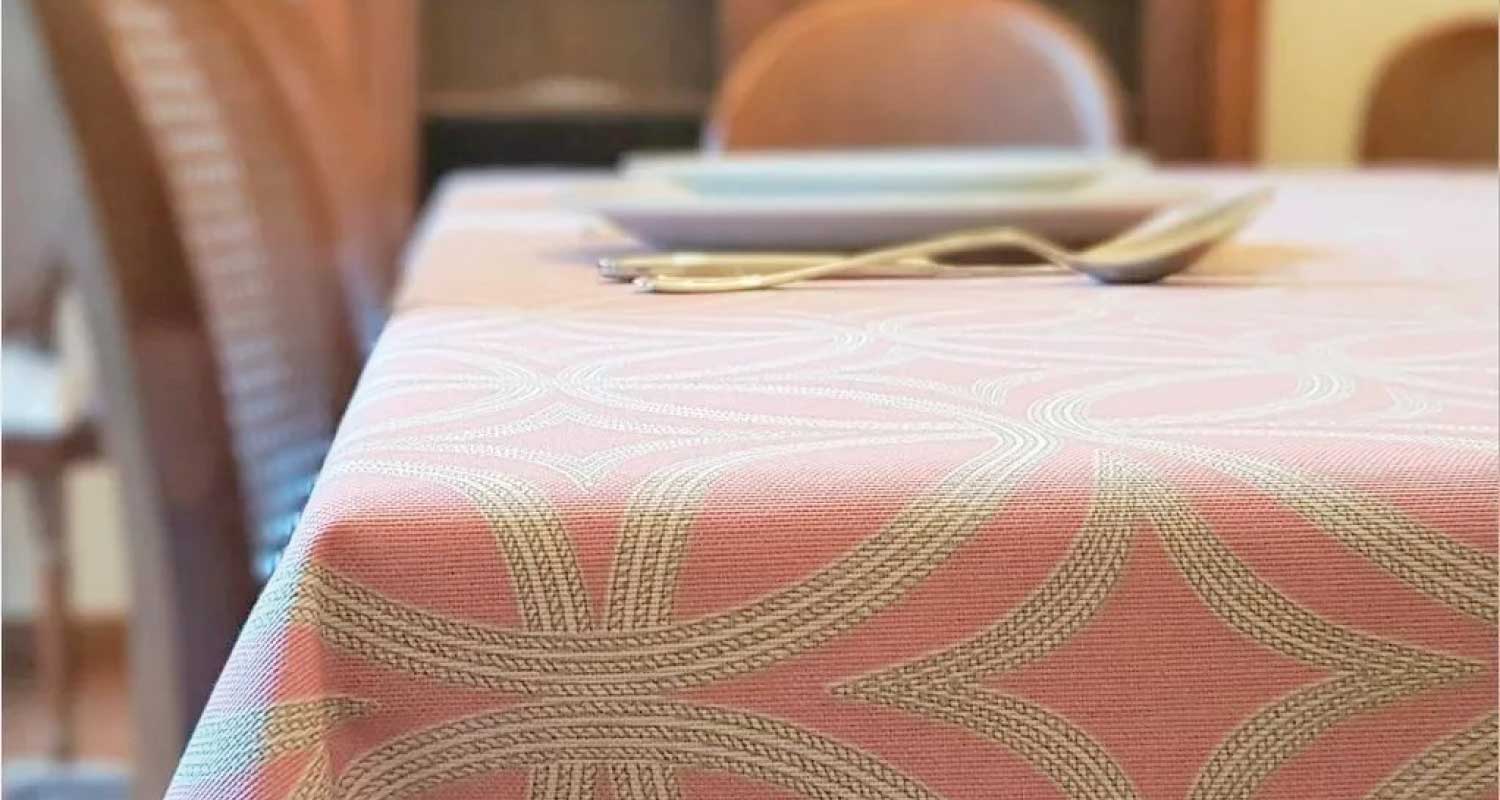 atelier-caral-detalle-mantel-antimanchas-rosado-bodega-italia Detalle de mantel antimanchas rosado con patrón entrelazado en comedor elegante – Atelier Caral