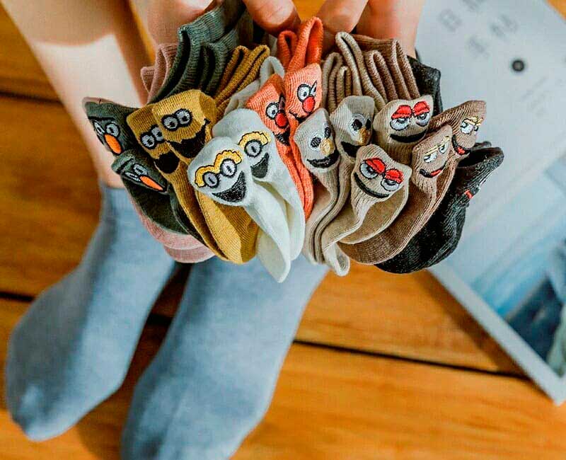 calcetas-divertidas-caritas-colores-capitan-style Pack de calcetas con caritas bordadas en distintos colores sostenidas en manos – Capitán Style en Bodega Italia