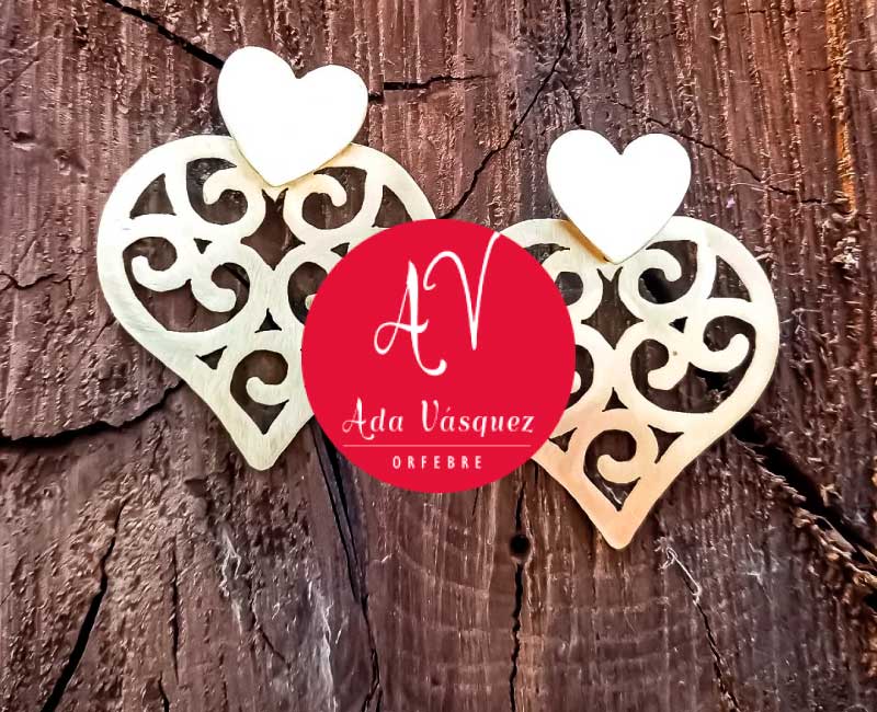 oyería artesanal de Ada Vásquez Orfebre, diseño de corazones calados sobre fondo rústico en Bodega Italia