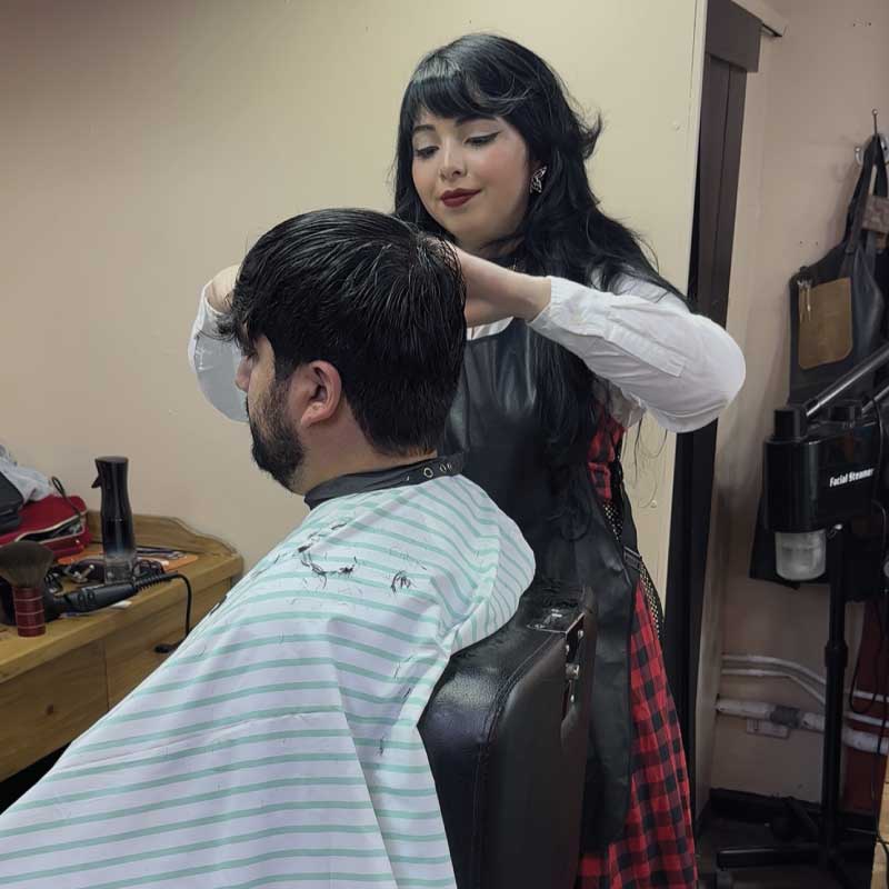 Barbera de Pols Barber realizando un corte de cabello masculino a un cliente, con atención personalizada en Bodega Italia, Providencia.