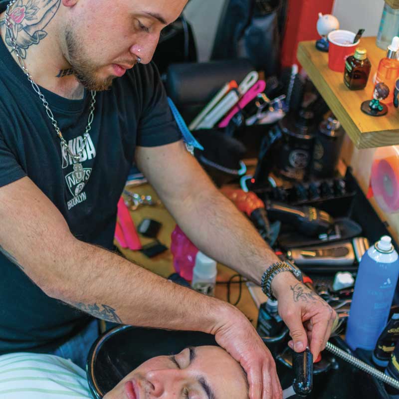 Barbero de Pols Barber realizando un lavado de cabello a un cliente en el lavapelos de la barbería en Bodega Italia, Providencia.