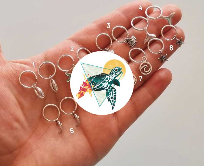 Aros de plata 925 con dijes marinos exhibidos en la mano, diseño de Tatuara en Bodega Italia
